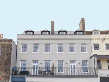 A four-story building with multiple windows and a balcony with outdoor furniture at 6 The Beaches in Weymouth