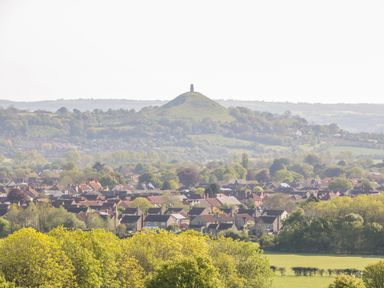 A town with houses and trees with a hill and tower in the background at Bluebell in Sticklinch West Pennard Glastonbury