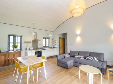 An open plan kitchen and living area with a grey sofa and yellow chairs at Bluebell in Sticklinch West Pennard Glastonbury