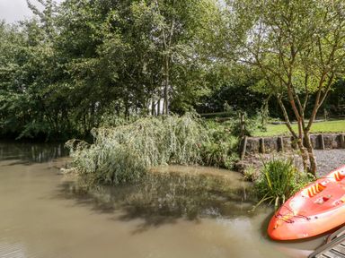 A small body of water with trees and an orange kayak at Bluebell in Sticklinch West Pennard Glastonbury