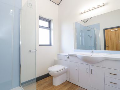 A bathroom with a toilet sink vanity unit glass shower enclosure and wooden door at Primrose in Sticklinch West Pennard Glastonbury