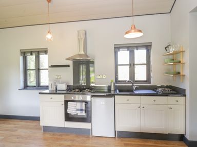 A kitchen with stove oven refrigerator sink shelves and two windows at Primrose in Sticklinch West Pennard Glastonbury