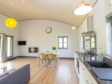 A kitchen and dining area with a table and chairs a sofa and wall clock at Primrose in Sticklinch West Pennard Glastonbury