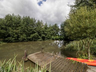 A wooden dock on a small lake with a metal ladder and a red kayak next to a tree at Primrose in Sticklinch West Pennard Glastonbury