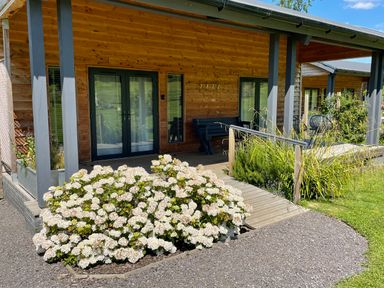 A wooden porch with glass doors and white flowers in front at Primrose in Sticklinch West Pennard Glastonbury