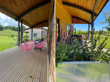A covered wooden deck with pink chairs and a table next to a wooden cabin with green grass and trees outside at Primrose in Sticklinch West Pennard Glastonbury