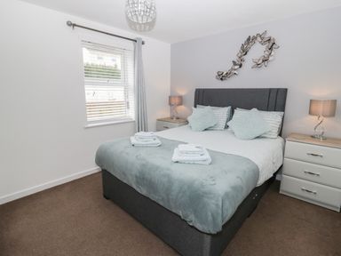A bedroom with a bed bedside tables lamps and a window at Bay View in Benllech
