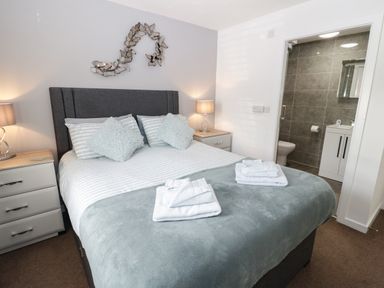 A bedroom with a double bed and two bedside tables with lamps and an adjacent bathroom at Bay View in Benllech