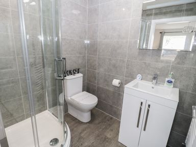 A bathroom with a shower cubicle toilet and a sink with cabinet at Bay View in Benllech