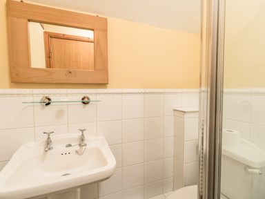 A bathroom with a corner sink and wooden framed mirror at Manor Farm Barn in Dewlish