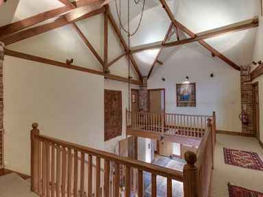 A hallway with wooden railings carpets on the floor and exposed wooden beams at Manor Farm Barn in Dewlish