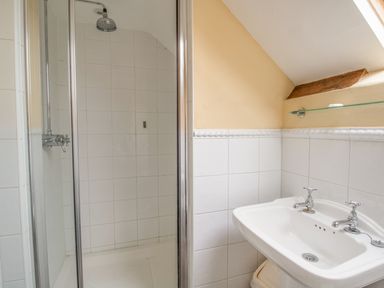 A bathroom with a shower enclosure and a sink under a slanted ceiling at Manor Farm Barn in Dewlish