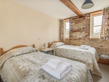 A bedroom with two single beds and a bedside table with a lamp at Manor Farm Barn in Dewlish