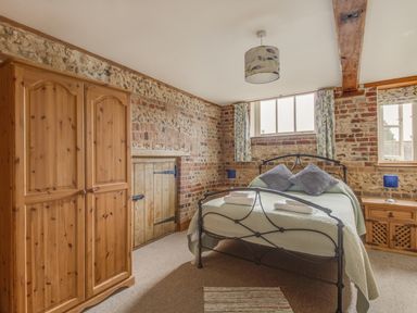 A bedroom with a metal bed frame two pillows two bedside tables and a wooden wardrobe at Manor Farm Barn in Dewlish