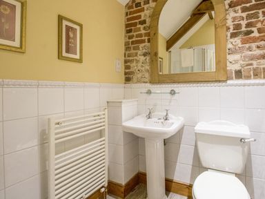 A bathroom with a sink toilet radiator and a mirror above the sink at Manor Farm Barn in Dewlish
