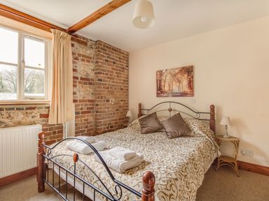 A bedroom with a double bed and folded towels on it at Manor Farm Barn in Dewlish