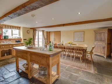 A kitchen with a wooden island and dining table with chairs at Manor Farm Barn in Dewlish