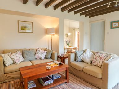 A living room with two beige sofas wooden coffee table and a floor lamp at Woodstock Cottage in Birchill near Chardstock