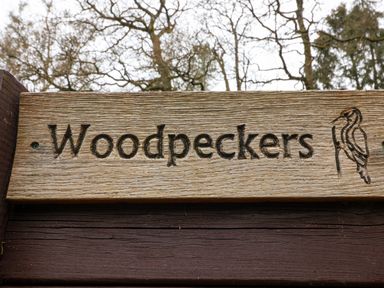 A wooden sign with the word Woodpeckers and a woodpecker illustration at Woodpeckers in Willand