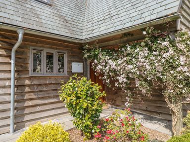 Exterior corner of a wooden house with a window a mailbox flowering vines and garden shrubs at Trevinny Lodge No 37 in Davidstow near Boscastle