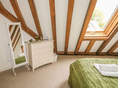A bedroom with a white dresser a standing mirror a green bedspread and a skylight window at Trevinny Lodge No 37 Davidstow near Boscastle