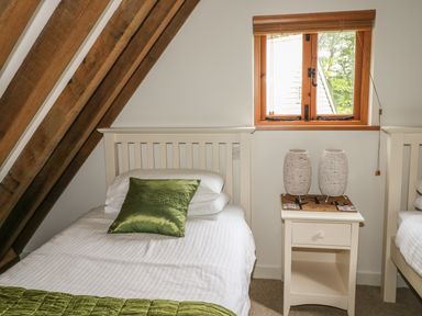 A bedroom with two single beds a nightstand with two lamps and a window at Trevinny Lodge No 37 Davidstow near Boscastle