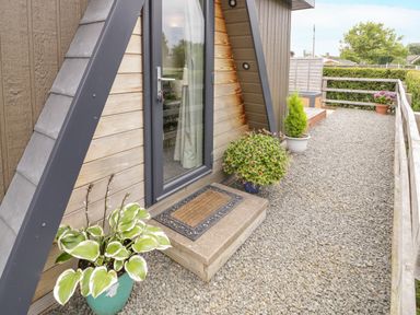 An outdoor gravel area with potted plants a glass door and wooden railings at Alstroemeria Bretforton near Evesham