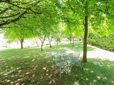 A table and chairs under trees in a garden at Pheasant Cottage in Priston Village, BATH