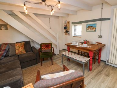 A living room with a dining area and staircase at Farmhand Cottage near Narberth