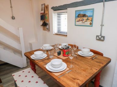 A dining room with a wooden table set for meals at Farmhand Cottage near Narberth