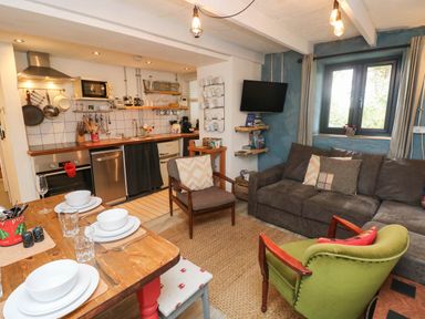 A kitchen and living room area with a sofa and dining table at Farmhand Cottage near Narberth