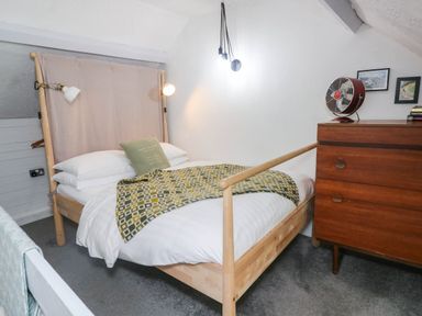A bedroom with a bed and chest of drawers at Farmhand Cottage near Narberth