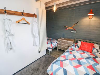 A bedroom with two beds and robes hanging at Farmhand Cottage near Narberth