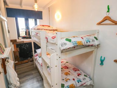 A bedroom with bunk beds and a window at Farmhand Cottage near Narberth