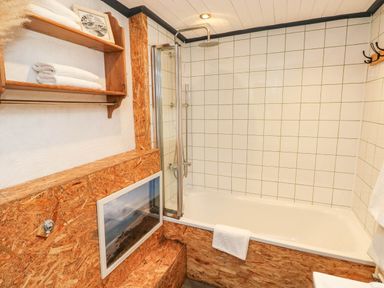 A bathroom with a shower and a bath at Farmhand Cottage near Narberth