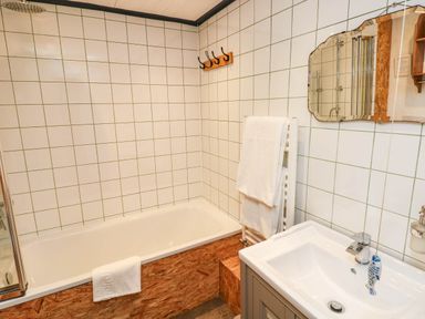 A bathroom with a bathtub and washbasin at Farmhand Cottage near Narberth