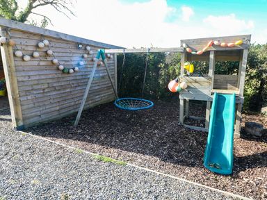 An outdoor play area with a swing and slide at Farmhand Cottage near Narberth