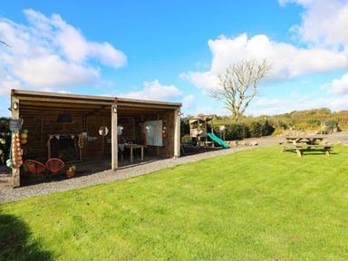 An outdoor area with a playground and table at Farmhand Cottage near Narberth
