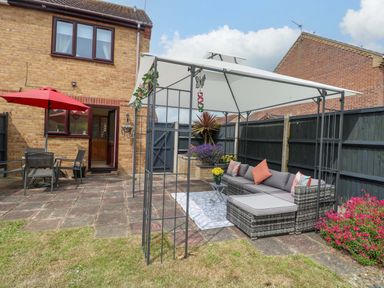 A garden with outdoor seating and a patio at Breydon Cottage in Bradwell near Gorleston-On-Sea