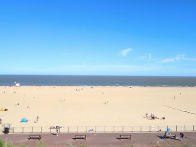 A beach with people and benches at Breydon Cottage Bradwell near Gorleston-On-Sea