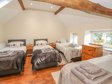 A bedroom with four single beds wooden floor exposed ceiling beams and wooden furniture at The Old Coach House in Llanarmon Yn Ial