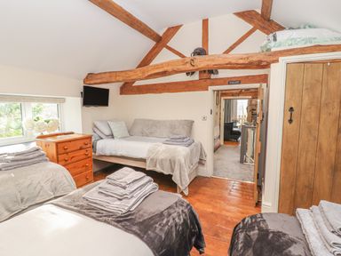 A bedroom with wooden beams beds a dresser and a window at The Old Coach House in Llanarmon-Yn-Ial