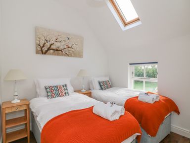 A bedroom with two single beds bedside tables lamps and a skylight window at The Old White Cottage in Shillelagh County Wicklow