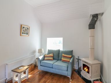 A living room with a blue sofa and wood burning stove at The Old White Cottage in Shillelagh County Wicklow