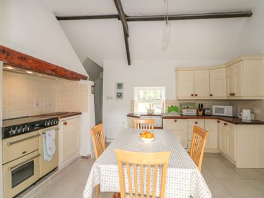 A kitchen with a dining table and chairs an oven sink cabinets and appliances at The Old White Cottage in Shillelagh County Wicklow