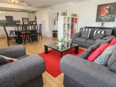 A living room with grey sofas and black dining table in an open plan kitchen at Tremar in Carbis Bay