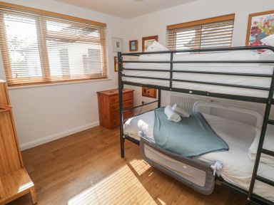 A bedroom with bunk beds a wooden chest of drawers and windows with blinds at Tremar in Carbis Bay