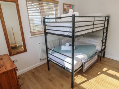 A bedroom with a metal bunk bed wooden chest of drawers and large mirror at Tremar in Carbis Bay