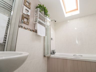 A bathroom with white sink and bathtub under a skylight at Tremar in Carbis Bay