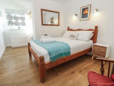 A bedroom with a wooden bed a white dresser and a wooden nightstand with drawers at Tremar in Carbis Bay